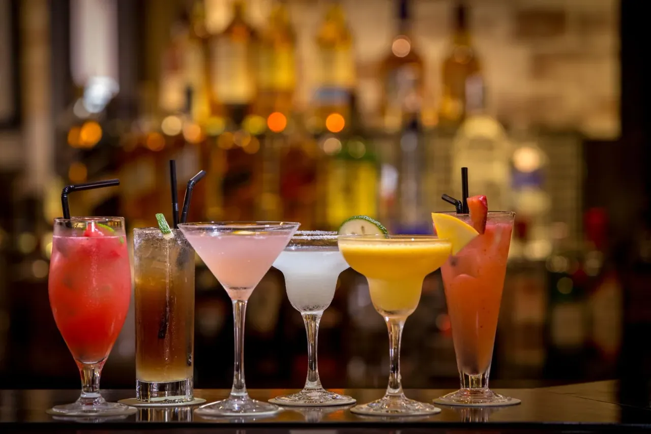 En række farverige cocktails på en bardisk.